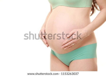studio shot of pregnant woman wearing green underwear touching her belly isolated on white
