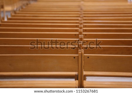 Indoor view of pattern of clear brown wooden benches in a french church. Abstract design with parallel lines, shadows and bright surfaces. Empty place for sitting. Graphic image with objects rows. 