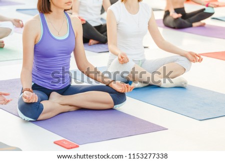 Group of happy cute young women sitting and stretching in yoga asana poses, meditation and workout training concept