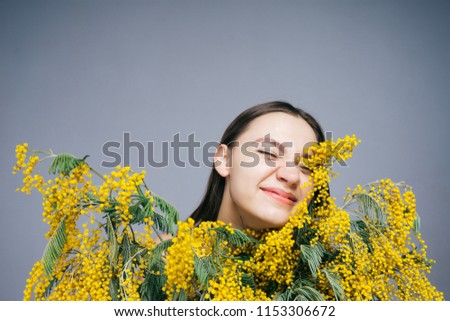 funny young girl enjoys spring and fragrant yellow mimosa