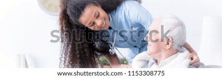 Panorama of happy caregiver supporting smiling elderly man in the nursing house