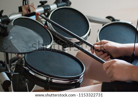 unrecognized boy practicing electronic drums with black drumsticks