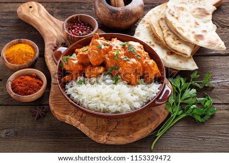 Chicken tikka masala spicy curry meat food in a clay plate with rice and naan bread on wooden background. Royalty-Free Stock Photo #1153329472