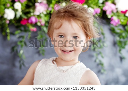 Portrait of the lovely little girl with  flowers. Looking at camera