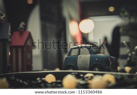 Blue and white small car toy model on the road. Mini car toy in the city near building on blurred background  with bokeh. Cartoon miniature car. World of imagination. Romantic dating night. 