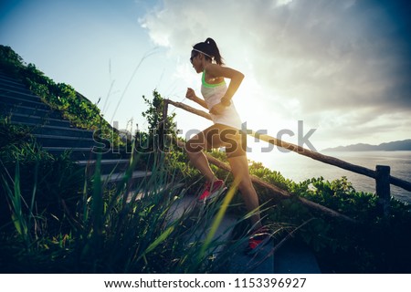 Determined woman running up on seaside mountain stairs Royalty-Free Stock Photo #1153396927