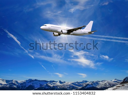 Airplane flying over sunny blue sky and Alpine mountains background