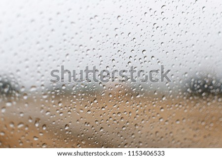 Close up of water drops standing still on a window glass of car after in a rain on rainy season with green forest background. Landscape view of natural water drop of rain on clear glass, Rain drops