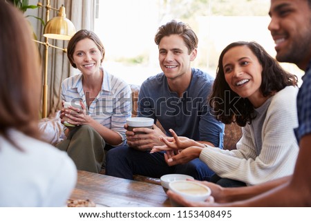 Friends relaxing around a table at a coffee shop, close up Royalty-Free Stock Photo #1153408495