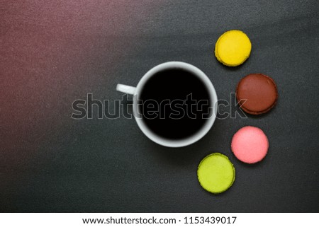 Top view cup of coffee and french macaron on black background, good morning