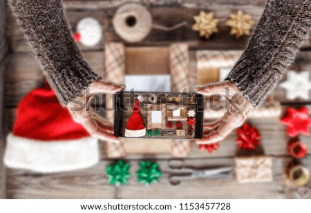 Christmas presents . Woman takes set of Christmas gifts on wooden table with a smartphone for instagram. Concept of technology, Christmas, people communication. Social networks