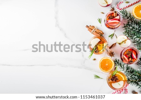 Traditional winter drinks, white and red mulled wine cocktail,  with white and red wine, spices, apple, orange. On white marble background copy space