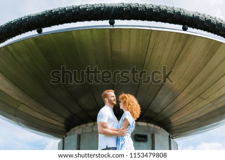 redhead couple embracing each other in front of modern building 