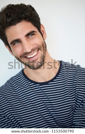 Smiling blue eyed guy ins striped top, looking away