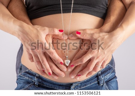 Belly of pregnant woman with hands of mom and dad