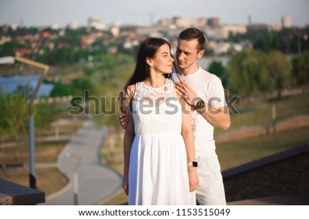 Love story of the beautiful young man and woman walking on the open air. embrace on a city walk.