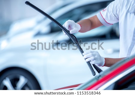 Technician is changing windscreen wipers on a car station. Royalty-Free Stock Photo #1153518346