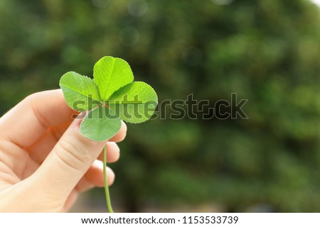 Woman holding four-leaf clover outdoors, closeup with space for text Royalty-Free Stock Photo #1153533739