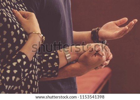 A couple holding hands praying.