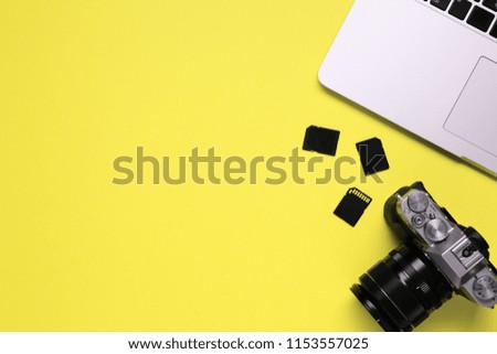 Top view of a desktop of a photographer consisting on a camera, a laptop, a notebook and a memory card on a blue desk background - copy space