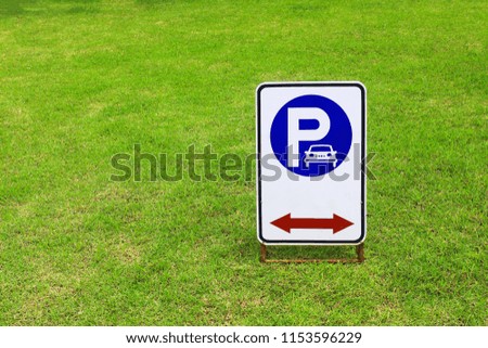 Parking signs are on green grass in the park.