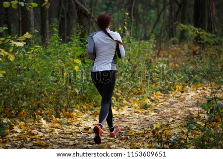 Photo from back of woman in sports clothes on run in autumn
