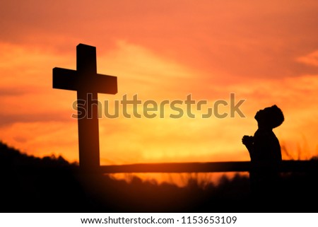 Boy praying to God with big cross and light of sunset background. christian concept.