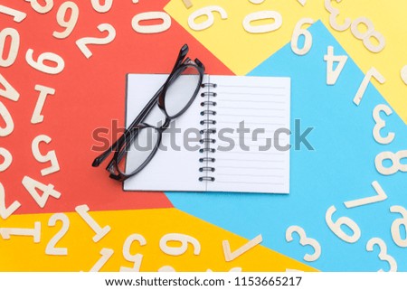notebooks and glasses in the center of colorful paper and scattered numbers