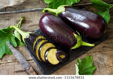 Fresh healthy raw Purple Eggplant on a kitchen wooden table. The concept of Diet menu.  Royalty-Free Stock Photo #1153678831