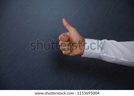 Young successful Businessman showing thumbs up. light anthracite Background with copy space for text. Cropped close up shot of a hand