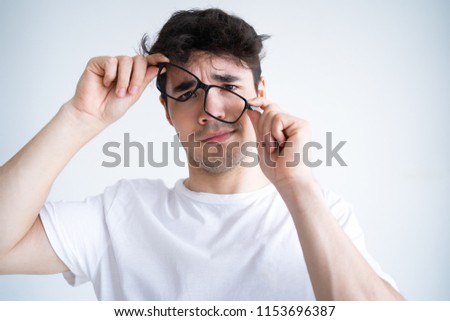 Upset handsome guy tired of wearing glasses. Sad mixed race young man failing in putting on eyeglasses. Wearing glasses concept Royalty-Free Stock Photo #1153696387