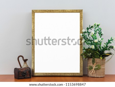 Empty Golden Frame On Wooden Shelf With Decorative Flowers,Vintage Box and Antique Vase.Gray Background Wall (White Blank Advertisement Banner Mock Up Isolated Template)