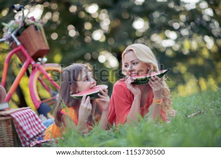 Mother and daughter enjoying together on picnic in park.