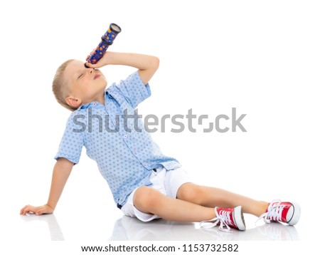 A cute little boy looks through a telescope or kaleidoscope. The concept of studying outer space and the surrounding world, a scientific discovery. Isolated on white background. Royalty-Free Stock Photo #1153732582