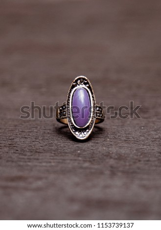 Silver ring with purple stone on black wooden table