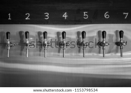 Beer tap row in bistro bar and cafe. With label number 1 to 7 at header board. Black and white or grey scale tone. Royalty-Free Stock Photo #1153798534