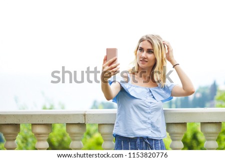 beautiful blonde young woman taking selfie in a park