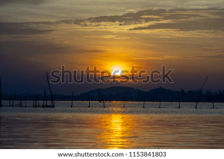 Sunrise view over the mountains and lake with cloudy sky.