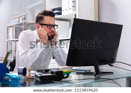 Stressed Young Businessman Sitting Near Computer In Office Royalty-Free Stock Photo #1153859620