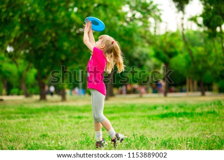Little girl play with flying disk in motion, playing leisure activity games in summer park