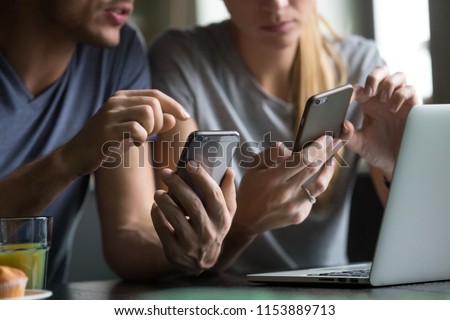 Close up view of man and woman using smartphones discussing mobile apps concept, couple talking holding cellphones synchronizing information online with laptop, checking news or texting messages Royalty-Free Stock Photo #1153889713