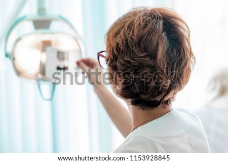 A dentist examines x ray in her hands