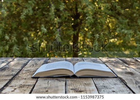 Open book on wooden table outdoors