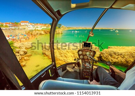 Helicopter cockpit interior flying on Praia da Rainha, small beach with cliffs in Cascais town, Portugal. Scenic flight above Lisbon coast skyline. The turquoise sea during summer holidays. Royalty-Free Stock Photo #1154013931