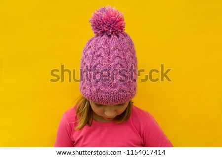 Fashion portrait happy young smiling woman wearing colorful pink knitted hat over yellow background. Copy Space Concept Lifestyle, Winter, Vacation.
