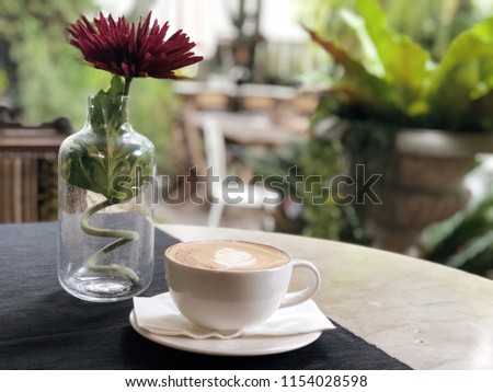 Cup of coffee latte art on table and nature burry bokeh background with copy space. (Selective focus)