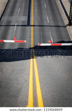 Draw bridge barricade arm with lifting roadway in the blurry background, and space for text on top and bottom