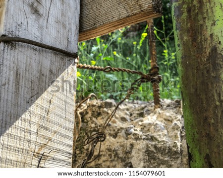 The texture of the loosened concrete wall, the construction of wooden beams, the iron reinforcement against the background of green grass.
