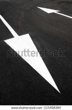 Opposite directions: two up and down white arrows on black asphalt. Challenge contradiction dilemma doubt confusion indecision, pros cons, positive negative, strengths weaknesses, input output, yes no