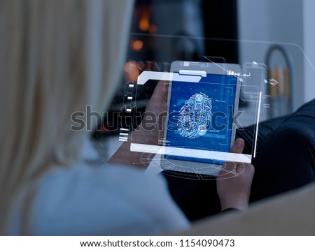 beautiful young woman surfing web using tablet computer with futuristic hud interface in front of fireplace on cold winter day at home